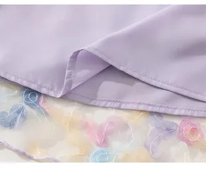 Detail of purple dress hem featuring double layers and rainbow butterfly embroidery