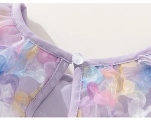 Detail of purple tulle dress showing 3D floral appliques and a single pearl button closure