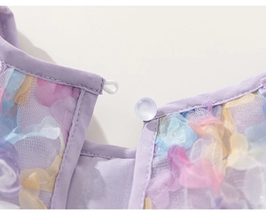 Detail of a purple tulle dress featuring 3D pastel floral appliqués and a pearl button