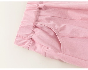 Detail of pink cotton trousers showing elastic waistband and curved side pockets