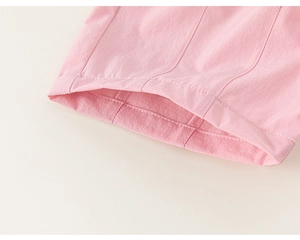 Detail of pink girls' trousers featuring reinforced double stitching and soft fabric texture