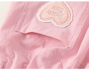 Macro detail of pink cotton pants featuring a heart-shaped Butter Bear embroidery