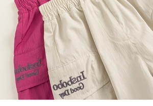 Detail view of kids cargo shorts with elastic waist and letter embroidery in rose and beige