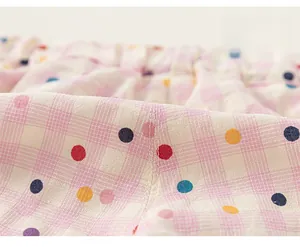 Gros plan sur les coutures de qualité et le motif à pois colorés du pantalon pour fille