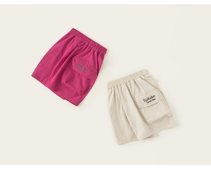 Detail of rose red and beige cargo shorts featuring elastic waist and utility pockets