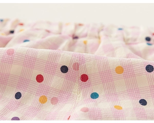 Vue détaillée du pantalon fille à pois colorés sur un tissu en coton à carreaux roses