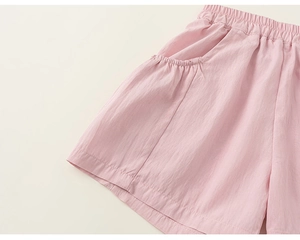 Detail of light pink summer shorts featuring elastic waist and side pockets for kids