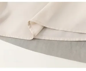 Detailed macro view of the finely stitched hem on a beige ink print mesh dress