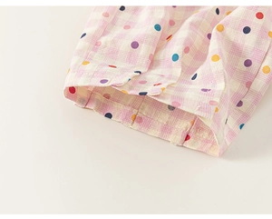 Détail du pantalon enfant à carreaux roses avec pois colorés et coutures précises