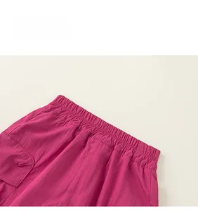 Detail of fuchsia cargo pants showing elastic waistband and stitching on durable fabric
