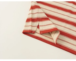 Vue détaillée de l'ourlet fendu sur le côté et des coutures d'un t-shirt à rayures rouges
