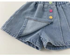 Dettaglio di gonne-pantalone in denim azzurro con bottoni colorati ed elastico in vita