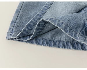 Dettaglio macro dell'orlo a doppia cucitura e trama diagonale di pantaloncini in denim azzurro