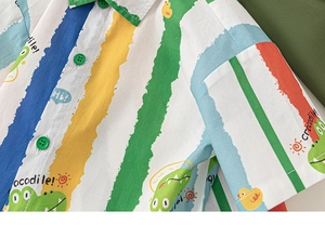 Detail of colorful striped boys' shirt featuring cute cartoon crocodile and duck prints