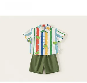 Detail shot of boys multi-color striped shirt with cartoon crocodile print and green shorts