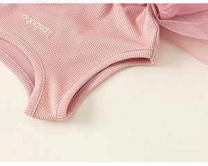 Detail of pink ribbed cotton dress featuring delicate embroidered text and mesh ruffles