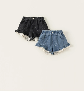 Detailaufnahme von Mädchen-Denim-Shorts mit Punkten und weißem Spitzenbesatz in Grau und Blau