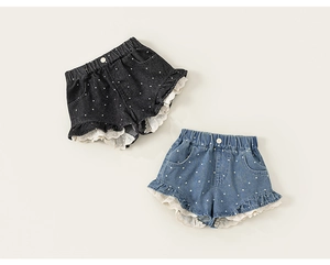 Detail von Mädchen Denim-Shorts mit weißen Punkten und Rüschensaum mit Spitzenbesatz