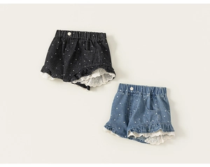 Detailansicht von zwei Jeans-Shorts für Mädchen mit weißen Punkten und Spitzenbesatz am Saum