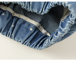 Detailaufnahme des elastischen Bundes und der weißen Punkte auf blauen Denim-Shorts