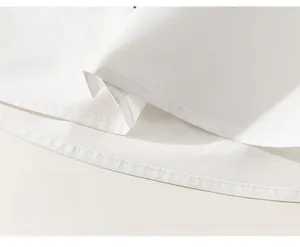 Detailed macro view showing the precise double-needle stitching on the white cotton shirt hem
