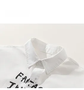 Close-up of white cotton boy's shirt featuring lapel collar and black graphic print