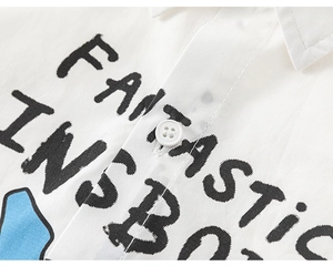 Detail of white cotton shirt showing the fantastic letter print and four-hole button