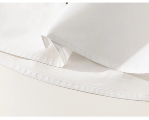 Close-up of white cotton shirt hem featuring precise stitching and high-quality fabric texture