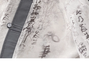 Détail d'une chemise chinoise traditionnelle pour enfant avec calligraphie et bouton manuel