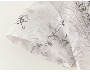 Gros plan sur le tissu translucide de la manche avec imprimé calligraphique et coutures fines