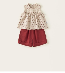 Detail of floral sleeveless top with ruffled collar and solid brick red shorts for girls