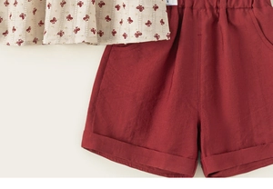 Detail of girls' summer cotton set featuring butterfly prints and red shorts pockets
