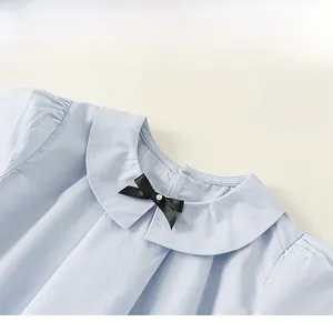 Détail du haut en coton bleu clair avec col Claudine et nœud orné de perles