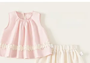 Détail ensemble bébé fille haut sans manches rose à dentelle et short crème