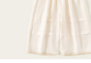 Vue détaillée du pantalon large crème avec coton texturé et bordure en dentelle