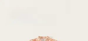 Detail of child cotton dress with orange gingham pattern and red floral print embroidery