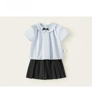 Détail de l'ensemble été fille avec chemise à col claudine bleu clair et jupe plissée noire