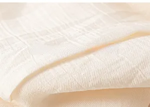 Gros plan sur un tissu en coton blanc cassé montrant la texture tissée et le toucher doux