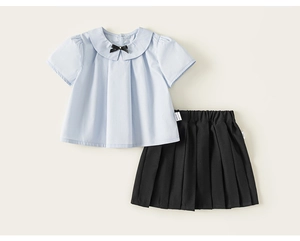 Détail d'un ensemble d'été pour fille avec chemise à col Claudine bleu et jupe plissée noire