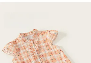 Detail of pink plaid cotton girl's dress with floral patterns and ruffled front buttons