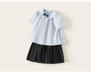 Détail d'un ensemble fille avec chemise bleue à col Claudine et jupe plissée noire
