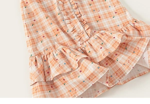 Detail of girls cotton plaid dress with star print and ruffle trim on the placket