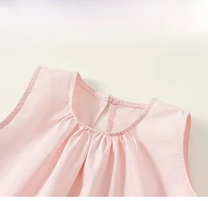 Détail d'un haut rose sans manches pour enfant avec col rond et bouton au dos