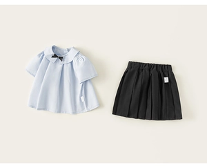 Détail à plat d'une chemise bleue à col claudine et jupe plissée noire pour fille