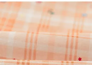 Close-up of orange plaid fabric with red stars, showing soft cotton texture and details