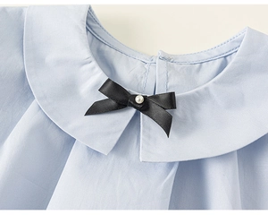 Détail du col Peter Pan bleu clair avec nœud en perles et finitions plissées chic
