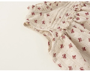 Detailed view of girls' sleeveless top with floral embroidery and ruffled collar lace trim
