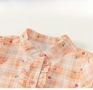 Detail of child's plaid shirt dress featuring star prints, ruffled collar and orange buttons
