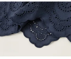 Detail von dunkelblauem Stickereistoff mit Blumenmuster, Ausschnitten und Wellensaum