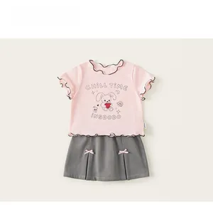 Detail von rosa Rüschen-T-Shirt mit Hasenprint und grauem Faltenrock mit Schleifen